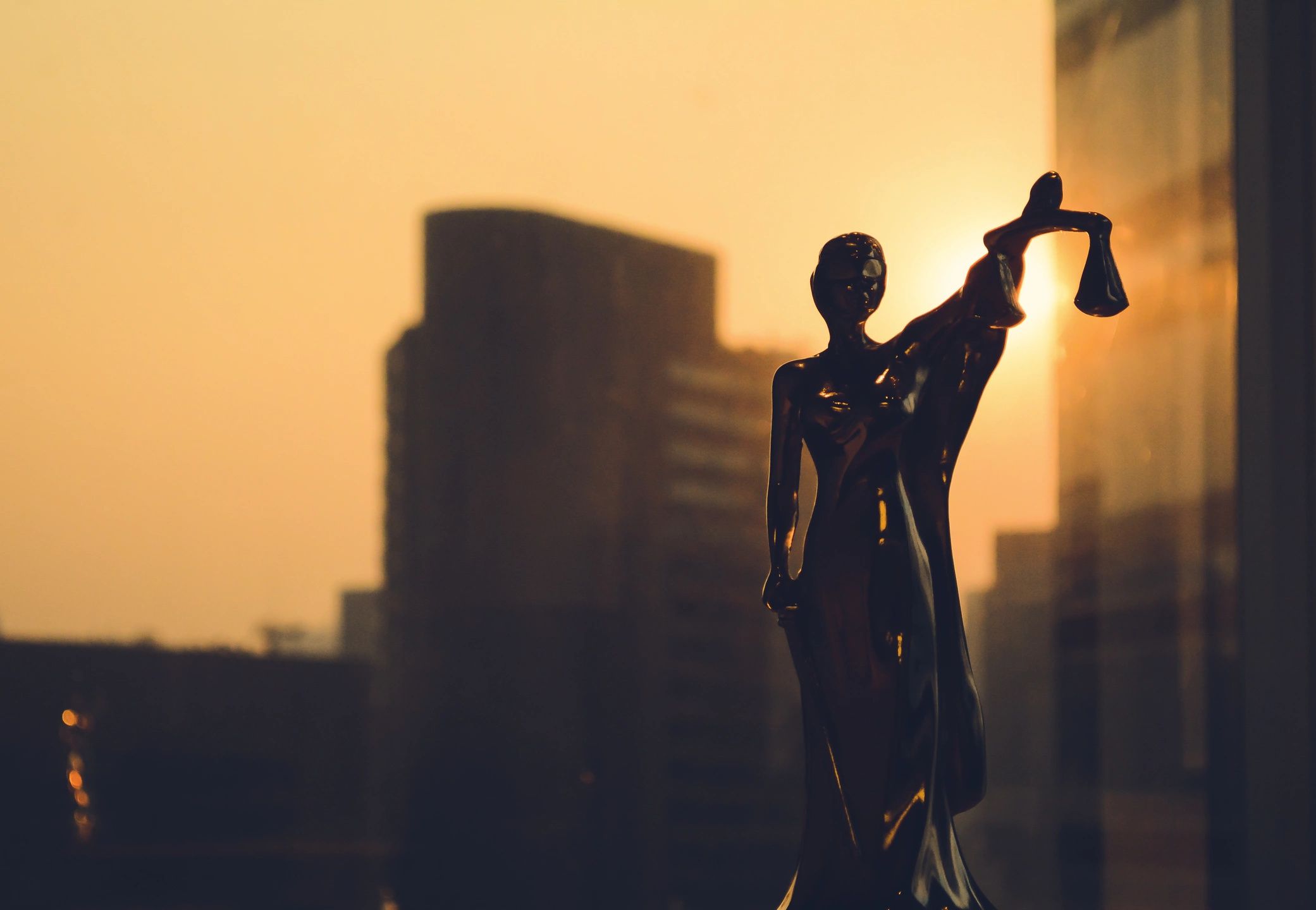 A statue of lady justice holding the hammer in front of a city skyline.